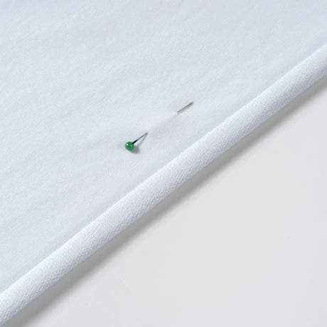 Close-up of white cotton French terry fabric showing a soft looped texture and rolled edge