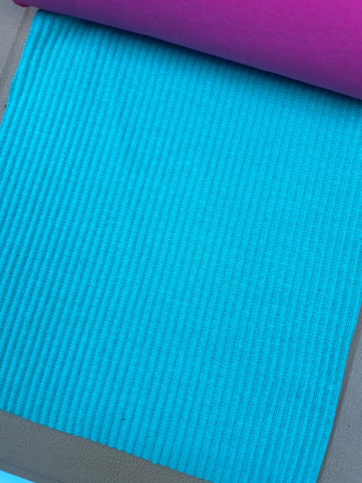 Close-up of turquoise rib knit fabric with raised vertical ribs in the DEC Fabrics material library