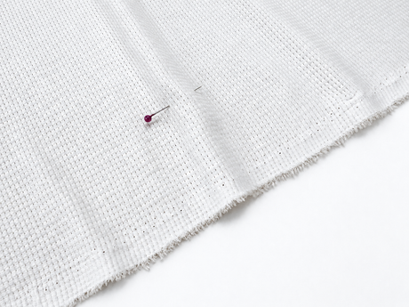 Single poly waffle knit fabric texture in a neutral white and gray weave
