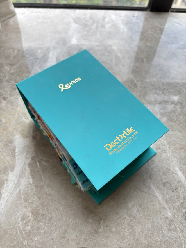 DEC Textile fabric sample booklet with a turquoise cover and fabric swatches visible along the edges